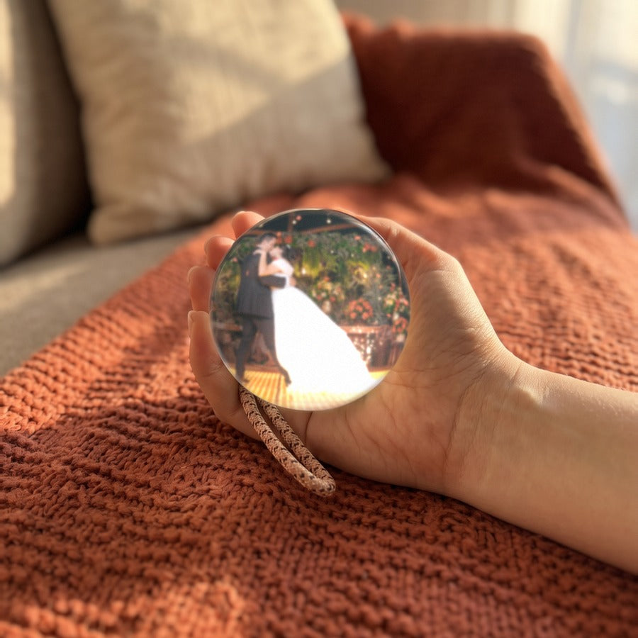 Una mano sostiene la esfera Orbalma encendida con el vídeo de una boda